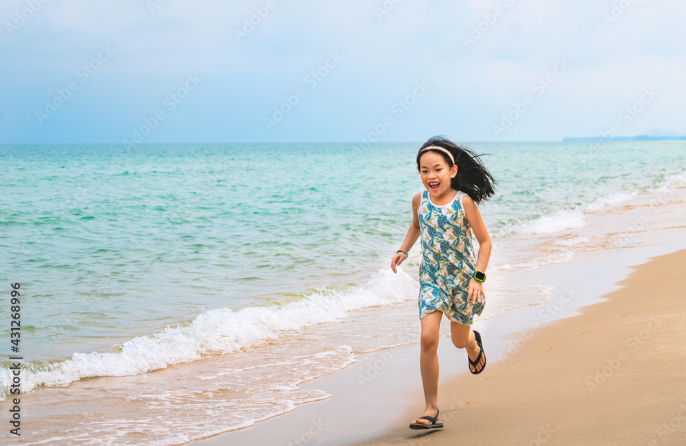 Happy little girl is running along the beautiful beach, motion blur, smiling face, wearing cute dress, black long hair, 7 years old, turquoise color ocean and blue sky. Space for copy and design. Happy little girl is running along the beautiful beach, motion blur, smiling face, wearing cute dress, black long hair, 7 years old, turquoise color ocean and blue sky. Space for copy and design.