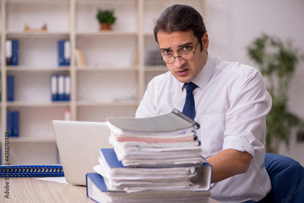 Young male employee and a lot of work in the office Young male employee and a lot of work in the office