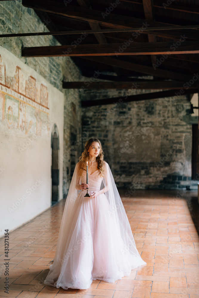 Bride with a candle in her hands walks along a loggia in an old villa on Lake Como
