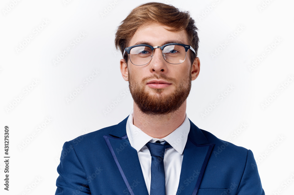 business man in a suit and glasses holds his hand near his face on a light background blue jacket tie classic business man in a suit and glasses holds his hand near his face on a light background blue jacket tie classic