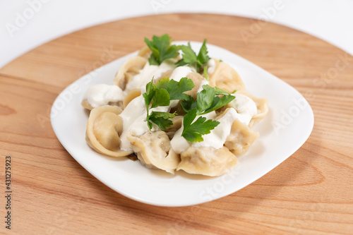 Dumplings with sour cream and herbs on a wooden background