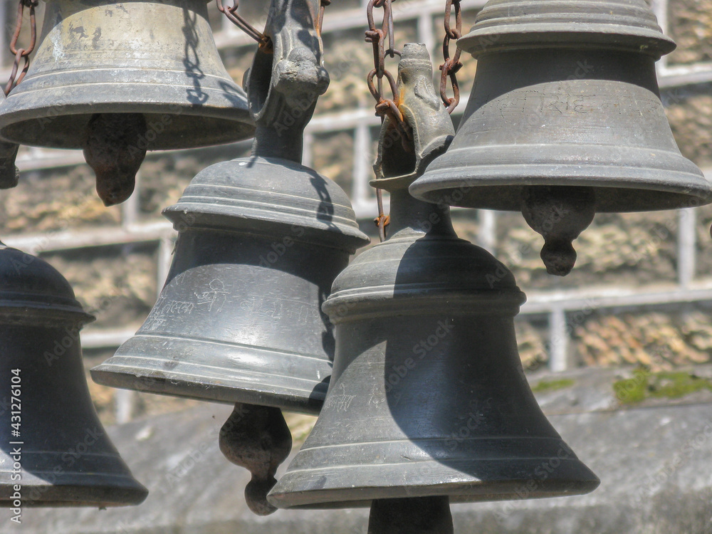 Selective focus image of Bells made of various metals hanging side by side outside Hindu Temples
