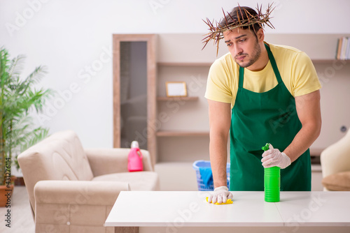 Young male contractor wearing prickly wreath on head cleaning th