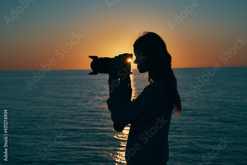 woman photographer silhouette at sunset near the sea side view