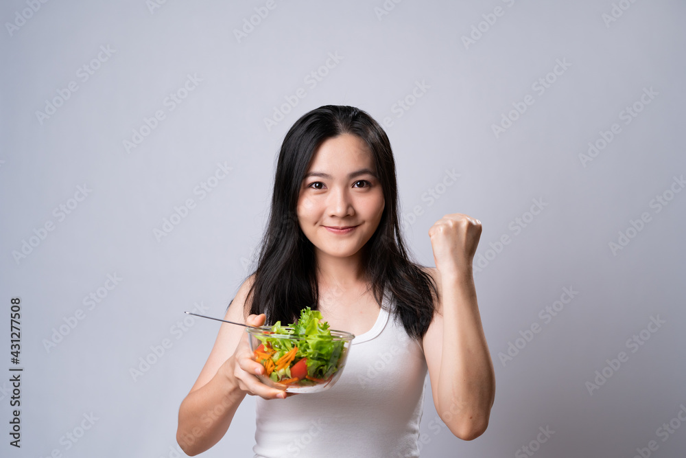 Asian woman eating salad isolated over white background. Asian woman eating salad isolated over white background.