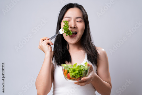 Asian woman eating salad isolated over white background.