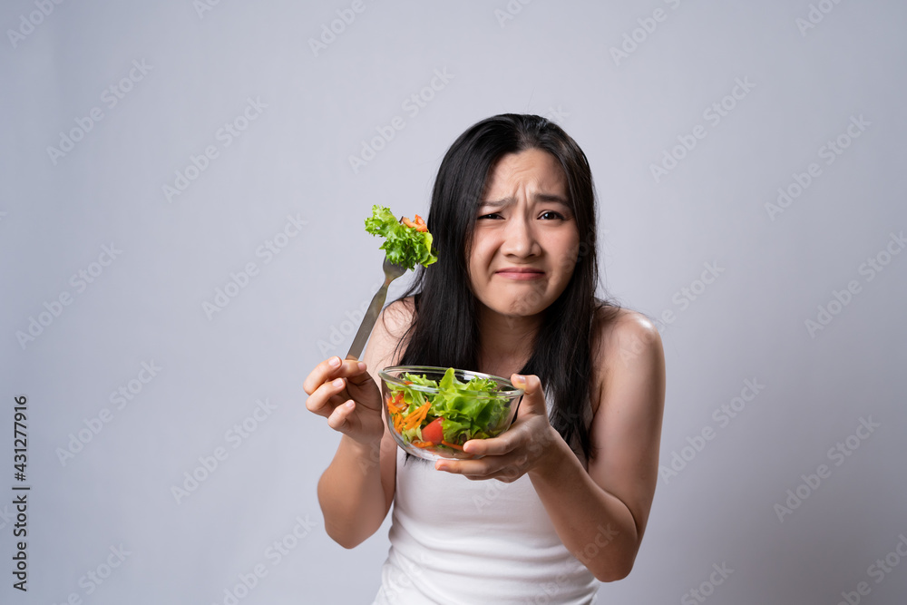 Asian woman trying to eat salad for diet isolated over white background. Asian woman trying to eat salad for diet isolated over white background.