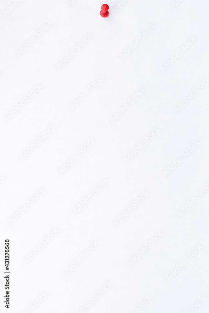 Vertical view. Close up white sheet of paper with red push pin on white background Vertical view. Close up white sheet of paper with red push pin on white background