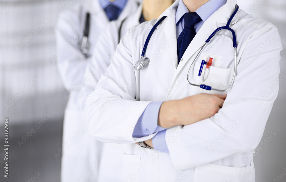 Group of modern doctors standing as a team with crossed arms and stethoscopes in hospital office. Physicians ready to examine and help patients. Medical help, insurance in health care, best desease Group of modern doctors standing as a team with crossed arms and stethoscopes in hospital office. Physicians ready to examine and help patients. Medical help, insurance in health care, best desease