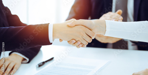 Businesspeople or lawyers shaking hands finishing up meeting or negotiation in sunny office. Business handshake and partnership