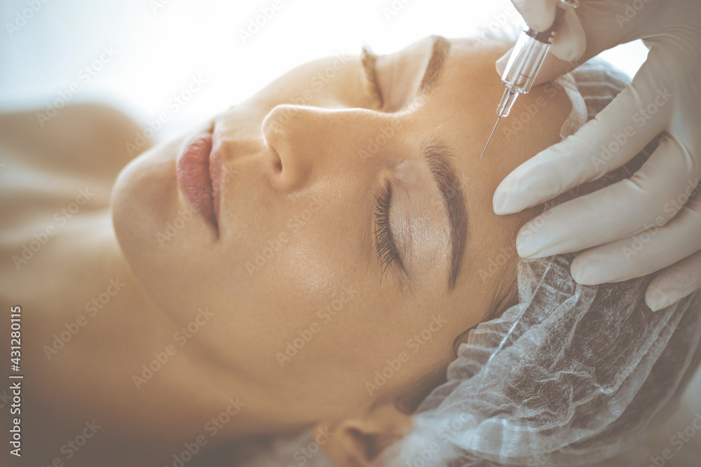 © rogerphoto - Beautician doing beauty procedure with syringe to face of young brunette woman in sunny clinic. Cosmetic medicine and surgery, beauty injections © rogerphoto - Beautician doing beauty procedure with syringe to face of young brunette woman in sunny clinic. Cosmetic medicine and surgery, beauty injections