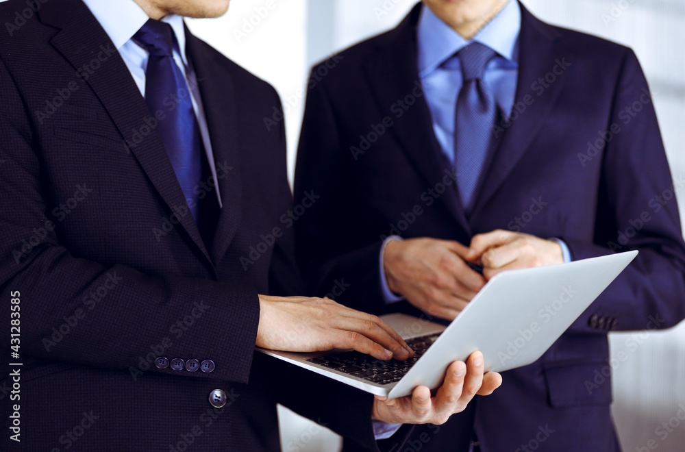 Business people discussing a presentation at meeting, standing in a modern office. Unknown businessman with a colleague search for some information at the laptop, lawyers at negotiation. Teamwork and Business people discussing a presentation at meeting, standing in a modern office. Unknown businessman with a colleague search for some information at the laptop, lawyers at negotiation. Teamwork and