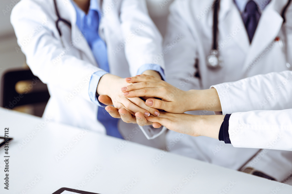 Obraz premium Group of modern doctors joining hands as a circle and ready to help patients. Teamwork in medicine during Coronavirus pandemic. Covid 2019