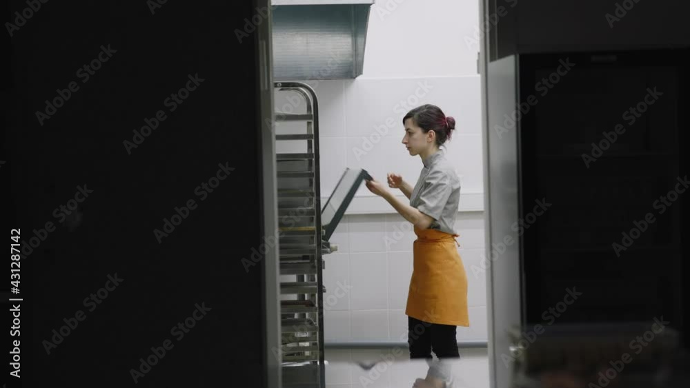The pastry chef checks the readiness of the dish in the oven The pastry chef checks the readiness of the dish in the oven