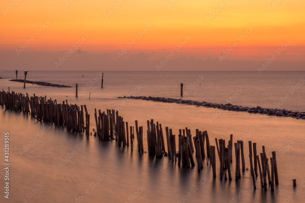 Bamboo wall and stone wall for protection against ocean waves. Sunset at the sea, Samut Sakhon, Thailand