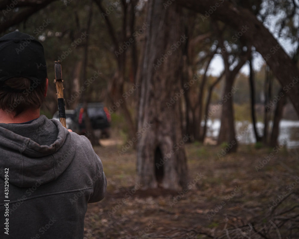 Rearview of Man Throwing axe to a Tree in a Riverside. Lifestyle and Nature Concept Rearview of Man Throwing axe to a Tree in a Riverside. Lifestyle and Nature Concept