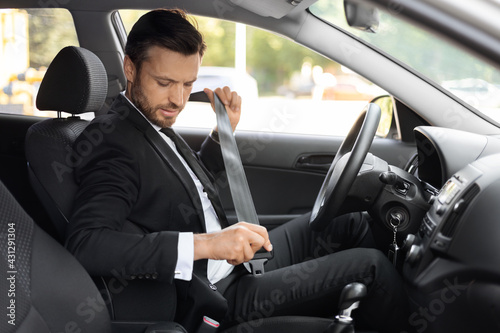 Businessman in suit fasten seat belt in his car © Prostock-studio