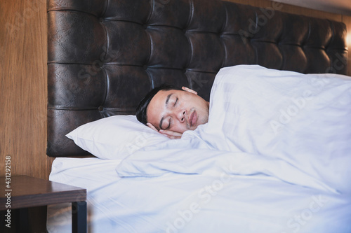 Asian man sleeping tightly on his comfortable bed at home