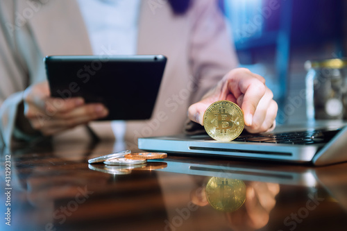 business hand using smartphone and laptop with golden bitcoin