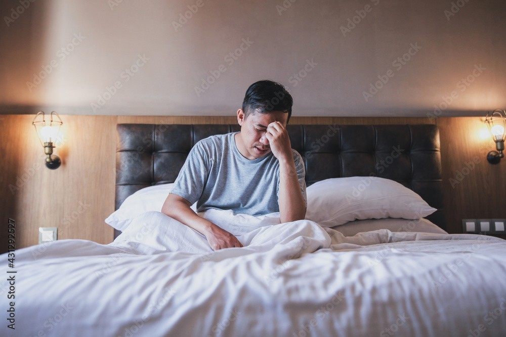 Asian man woke up on bed with headache or migraine Asian man woke up on bed with headache or migraine