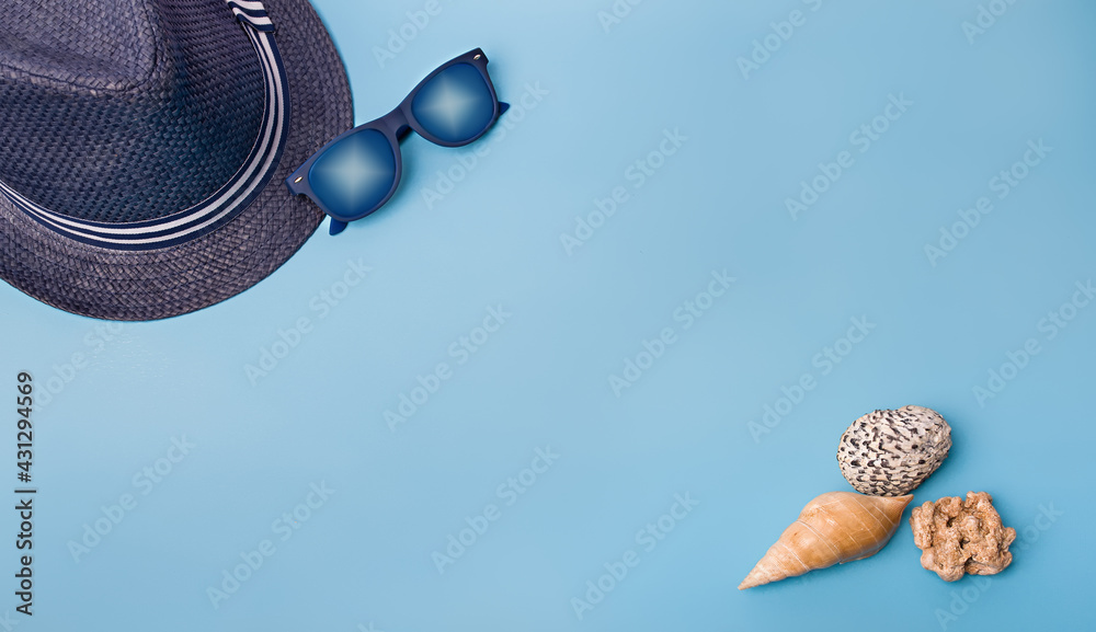 Flat lay of shells and hat on a blue background - obrazy, fototapety, plakaty 