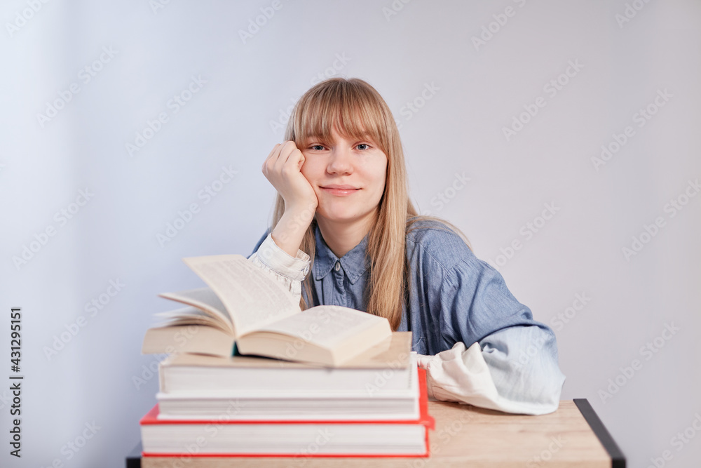 Educational, back to school or homeschooling concept. Blonde female student sitting with stack of books and looking straight in camera. Young beautiful caucasian pupil girl. High quality photo Educational, back to school or homeschooling concept. Blonde female student sitting with stack of books and looking straight in camera. Young beautiful caucasian pupil girl. High quality photo