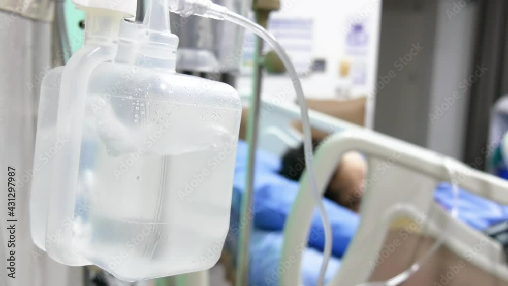Oxygen humidifier for nasal cannula, patient on hospital bed on blurred background. Oxygen humidifier for nasal cannula, patient on hospital bed on blurred background.