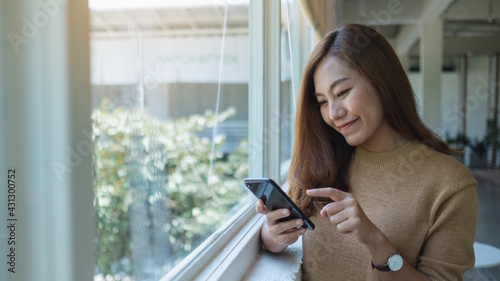 A beautiful young asian woman holding and using mobile phone