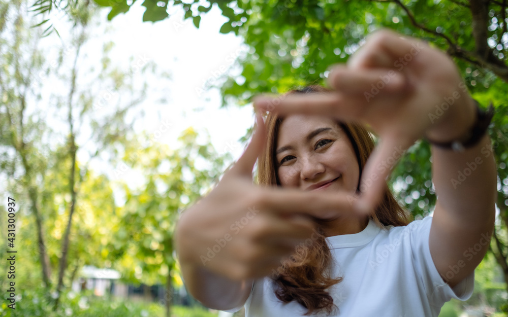 Portrait image of a beautiful asian woman raising hands and playing with camera in park Portrait image of a beautiful asian woman raising hands and playing with camera in park
