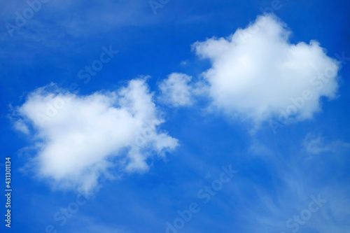 Fluffy white cumulus clouds floating on vibrant blue sky 
