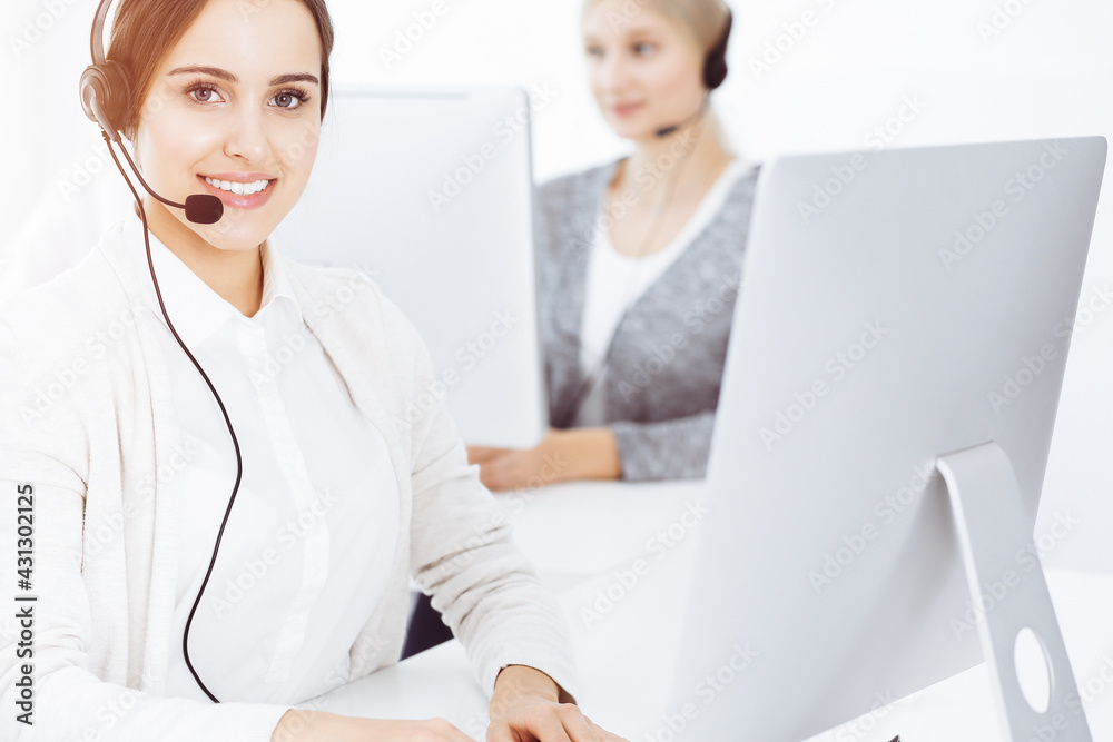 Call center in sunny office. Group of diverse operators at work. Beautiful woman in headset communicating with customers of telemarketing service Call center in sunny office. Group of diverse operators at work. Beautiful woman in headset communicating with customers of telemarketing service