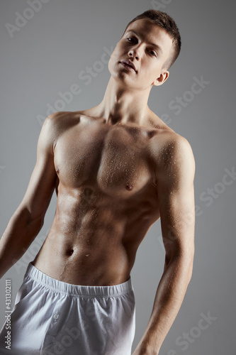 bodybuilder with a pumped up torso in white shorts on a gray background cropped view close-up