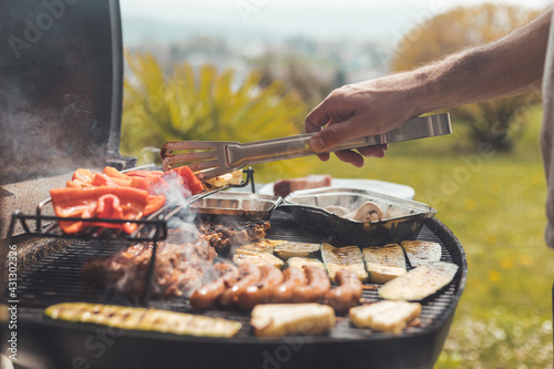 BBQ on weekend. Sausages, steak, cheese and vegetables on gas grill. Outdoors.