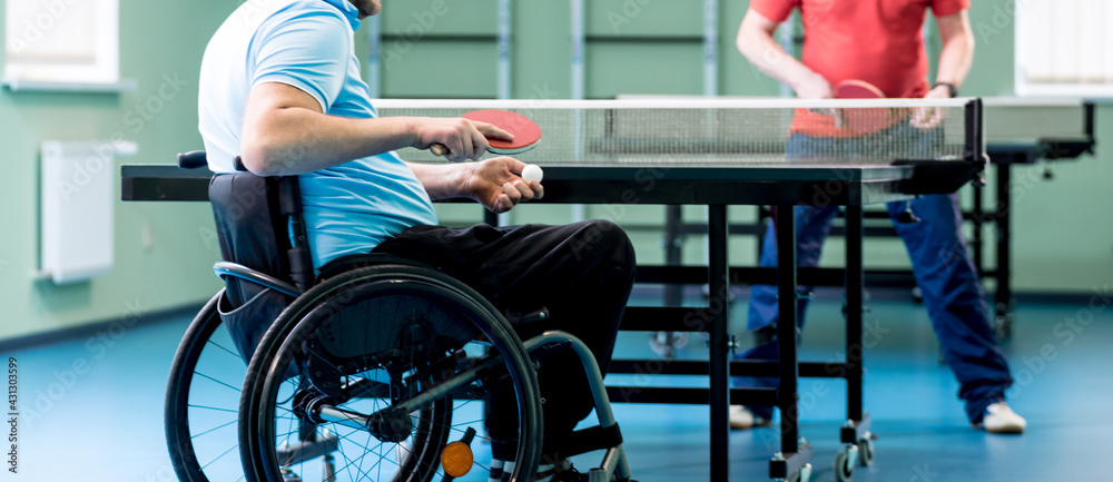 Fototapeta premium Adult disabled man in a wheelchair play at table tennis with his coach