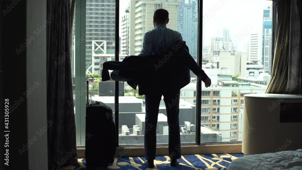 Businessman putting on jacket standing by window at home