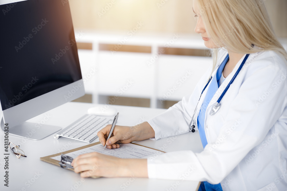 Unknown woman-doctor at work filling up medication history record form in sunny clinic, close-up Unknown woman-doctor at work filling up medication history record form in sunny clinic, close-up