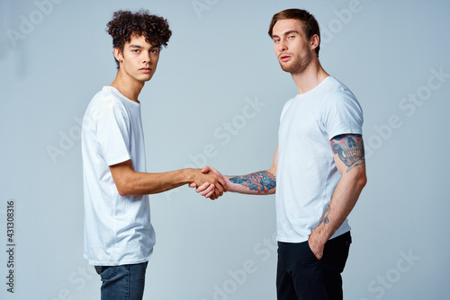 two friends hold hands in white t-shirts isolated background