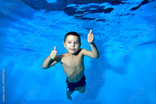 Portrait of a happy boy underwater, posing for the camera, smiling and giving a thumbs up. Concept. Close-up. Horizontal orientation of the photo.