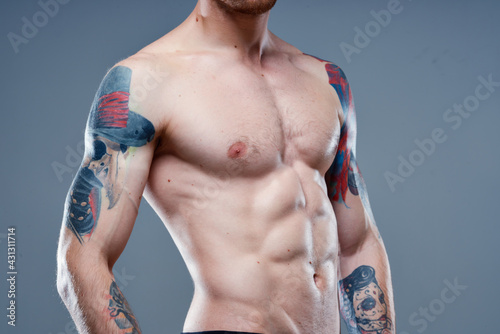 sexy athlete with naked torso and pumped up muscles tattoo gray background model
