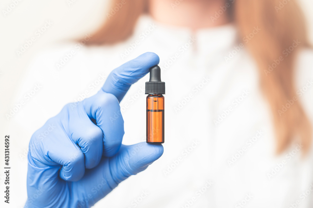 the doctor holds a vial of medicine in his hands, a bottle with drops the doctor holds a vial of medicine in his hands, a bottle with drops