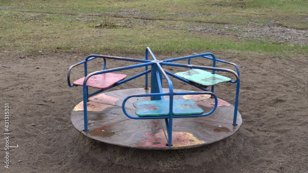 Children's rotating carousel in the park after rain. Spins without people. Children`s playground in the public park Children's rotating carousel in the park after rain. Spins without people. Children`s playground in the public park