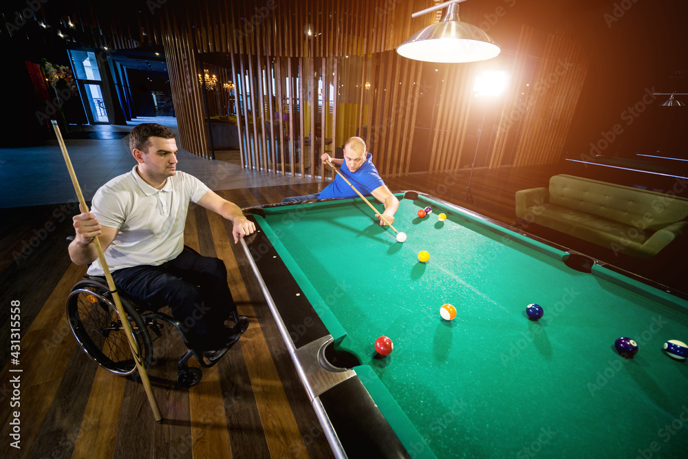 Fototapeta premium Adult men with disabilities in a wheelchair play billiards in the club