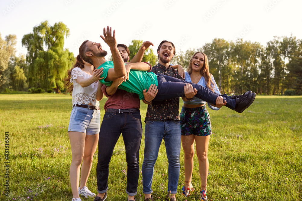 Cheerful young friends having fun in countryside on summer day. Group of people laughing and being silly in nature