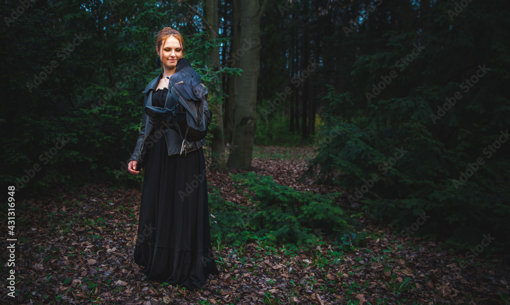 young woman or teenage girl in the forest with a big black raven on his hand young woman or teenage girl in the forest with a big black raven on his hand