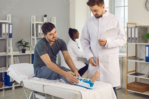 Tablou pe pânză Male patient with foot injury talking to orthopedic surgeon