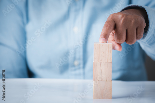 Hand holding wooden block cubes on table, business idea creative concept structure wooden block development leadership abstract background.