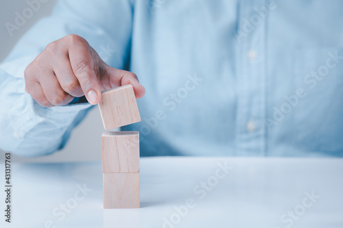 Hand holding wooden block cubes on table, business idea creative concept structure wooden block development leadership abstract background.