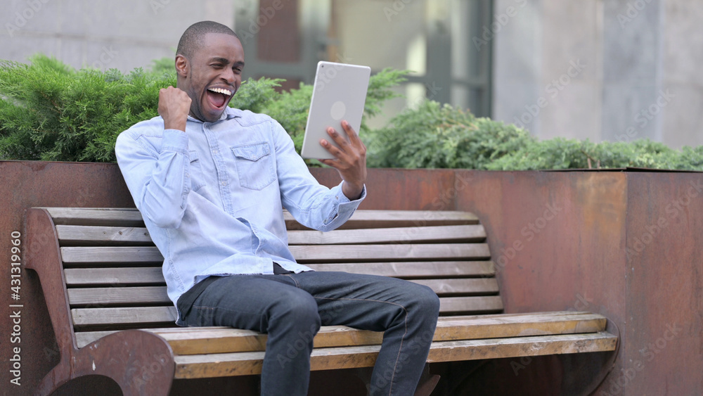 African Man Celebrating Success on Tablet Outdoor African Man Celebrating Success on Tablet Outdoor