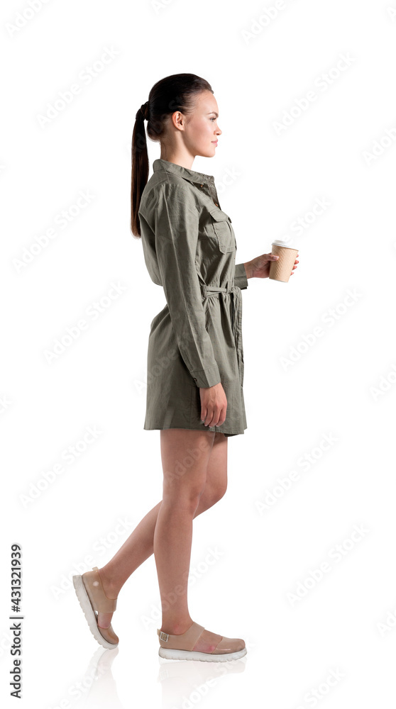 Full length side view portrait of young woman in green casual dress with takeaway coffee cup. Isolated over white background. Full length side view portrait of young woman in green casual dress with takeaway coffee cup. Isolated over white background.