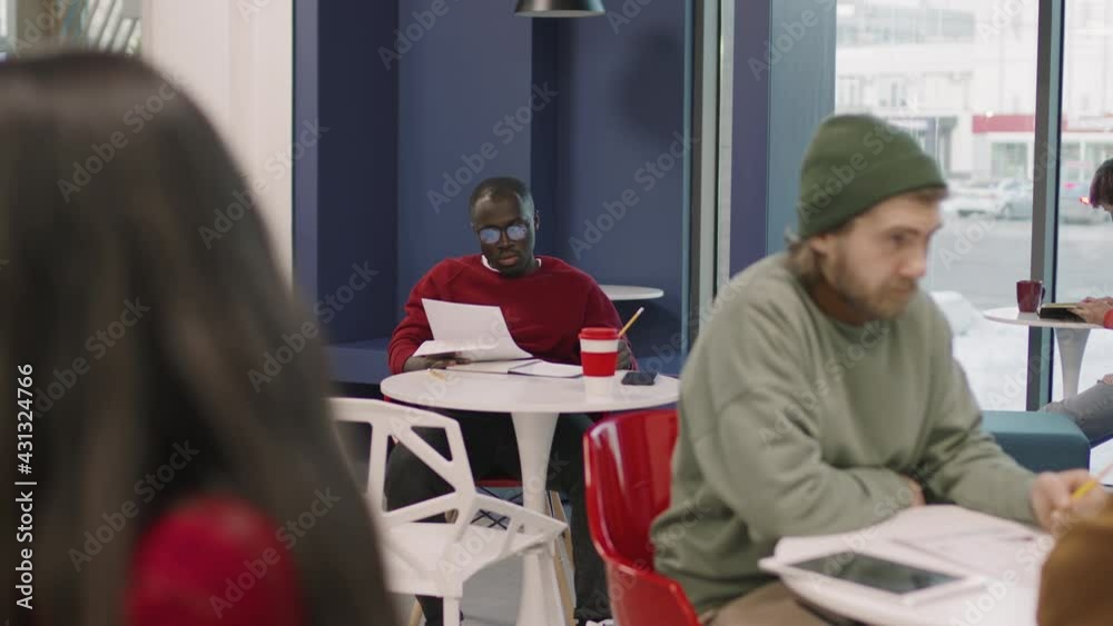 PAN slowmo of young businesspeople sitting at tables in office cafeteria and working on their projects PAN slowmo of young businesspeople sitting at tables in office cafeteria and working on their projects